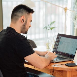 man with black headphones working at laptop