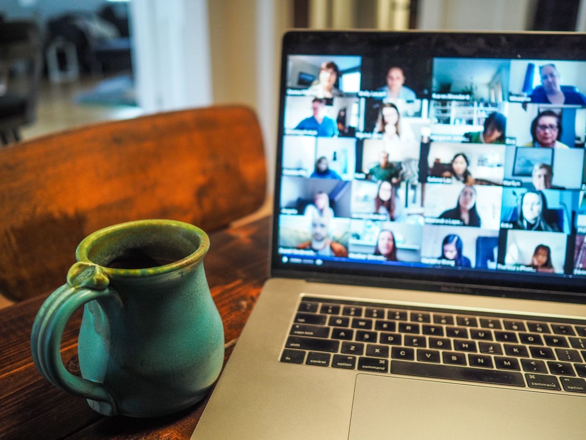 laptop computer with multiple faces on a video call with a mug of coffee