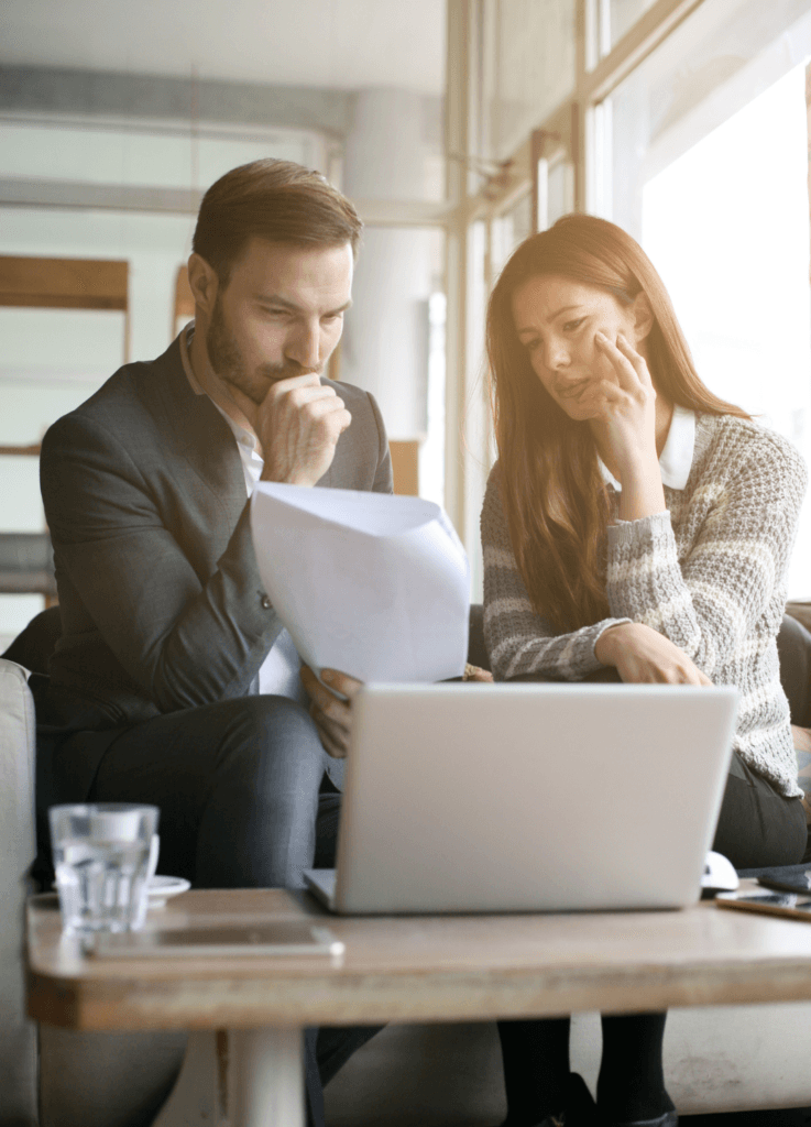 Man and woman looking over a document with a Laptop, used to illustrate the idea of reviewing the changes to zero hour contracts