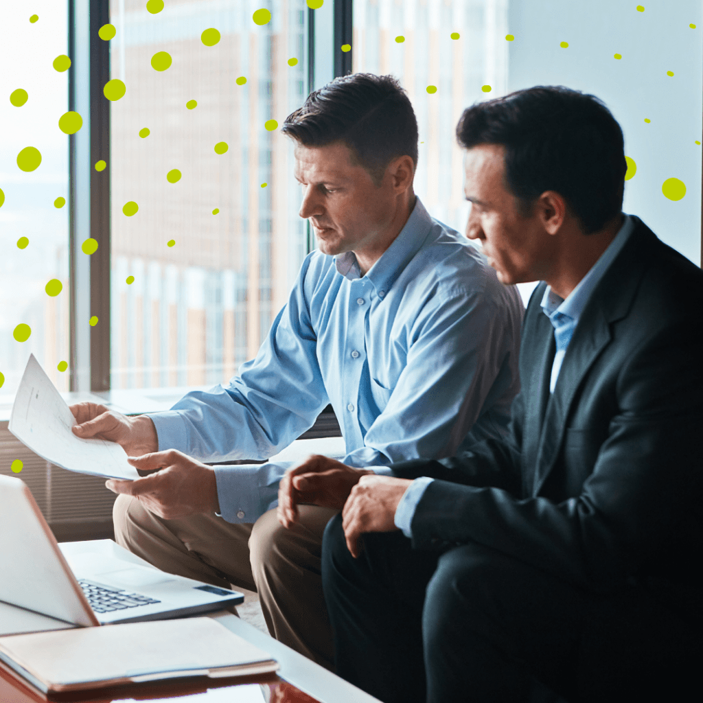 Two men sat reviewing papers in front of their laptops